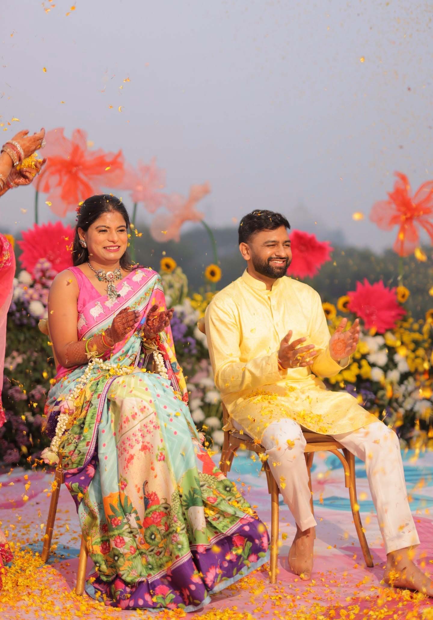 A colourful haldi celebration with the couple surrounded by flowers
